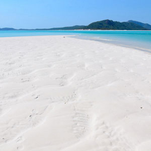 View along the white sand on Whitehaven Beach to aqua water and nearby islands