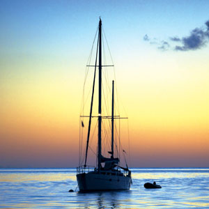 Silhouette of moored yacht and dinghy at sunset